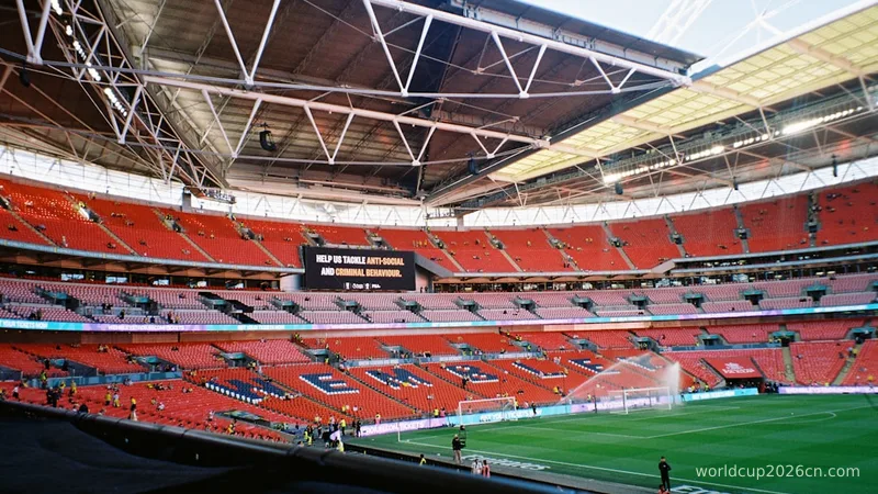 Empty stadium with red seats and green field.