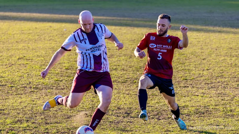 Two men playing soccer on a grassy field.
