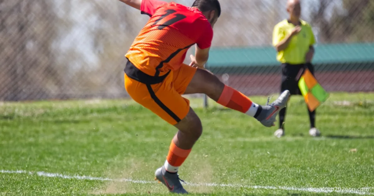 man in orange jersey shirt kicking soccer ball on green grass field during daytime
