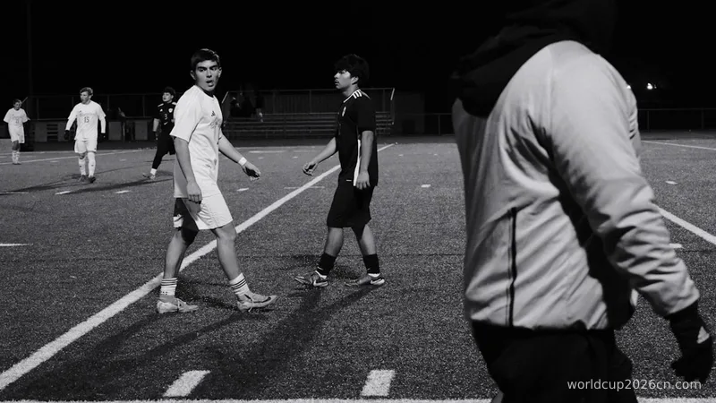 Young men playing soccer on a field at night