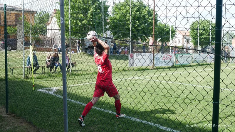 Goalkeeper in red uniform catching a soccer ball