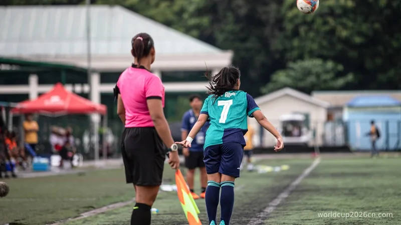A girl in a soccer uniform jumps for a ball