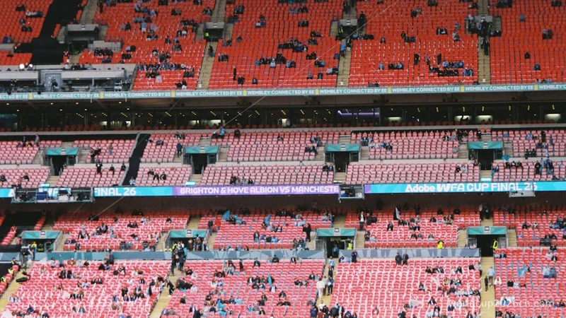 Red stadium seats with scattered spectators.