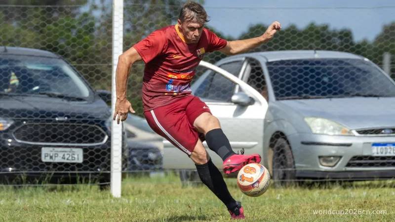 Man in red uniform kicking soccer ball on grassy field.
