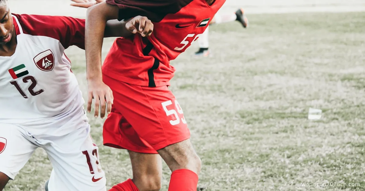 man in red and white soccer jersey kicking soccer ball on green grass field during daytime