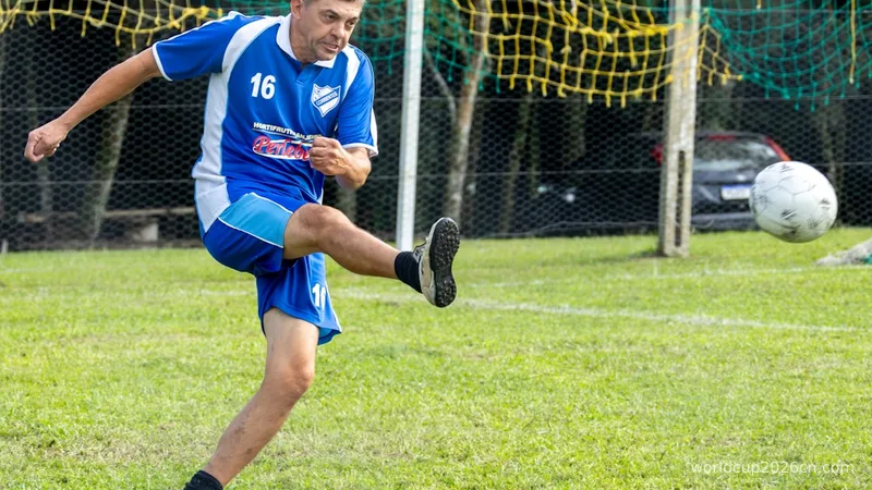 Man in blue uniform kicks soccer ball on field